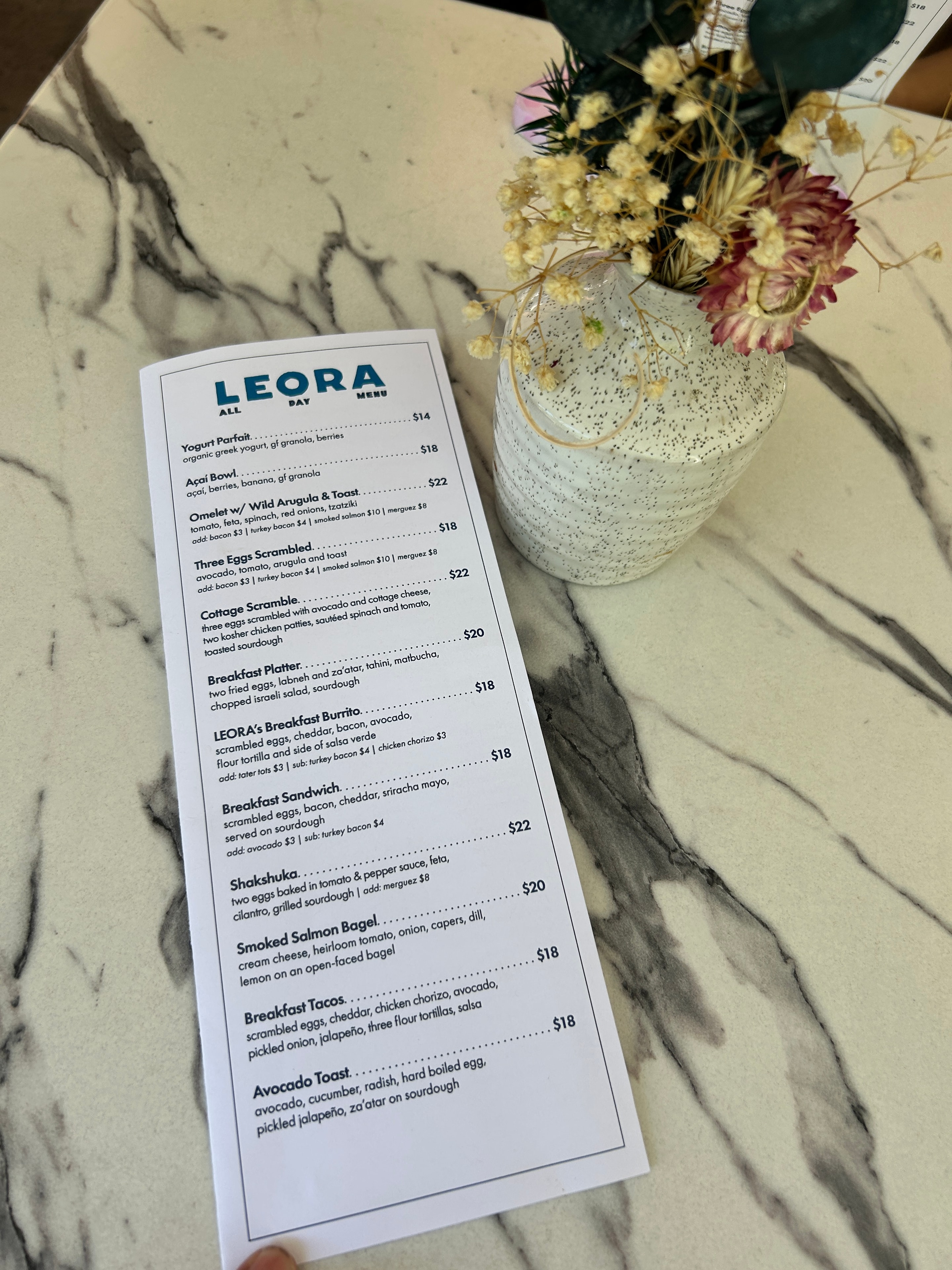 The Leora menu at Beverly Hills, photographed on the restaurant's marble surface.
